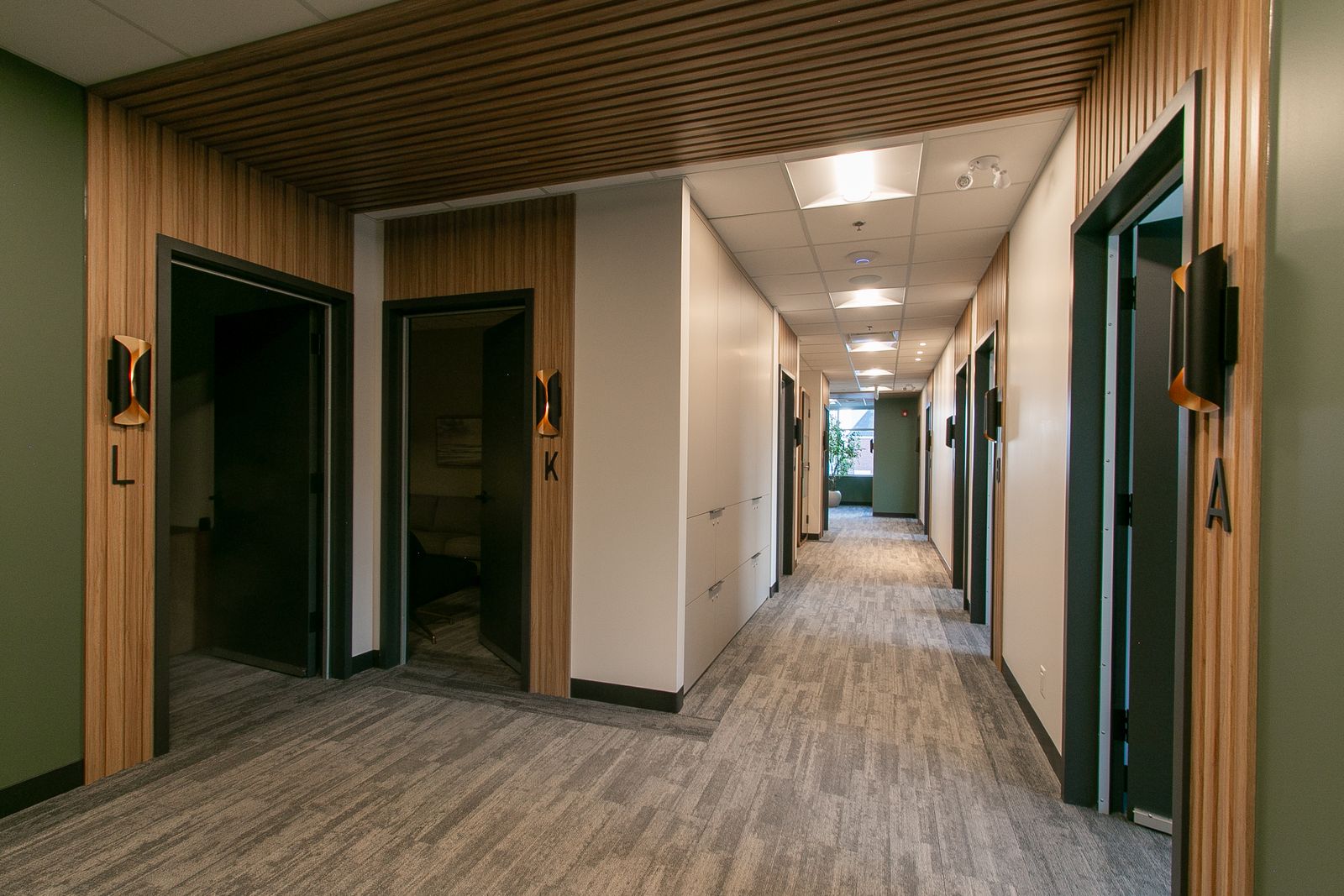 The Clinic Studios hallway with a wood slat ceiling and lettered signs beside each door